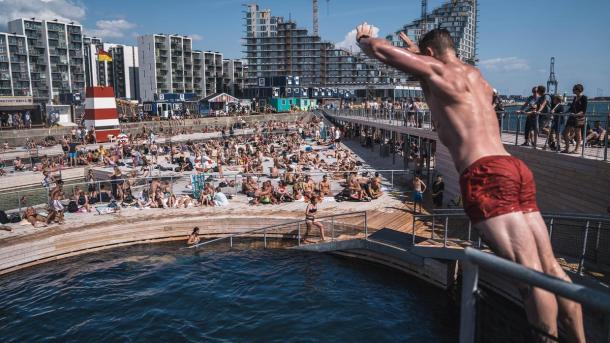 A man dives into Aarhus Harbour Bath, an open air saltwater swimming pool in Denmark, on a sunny day
