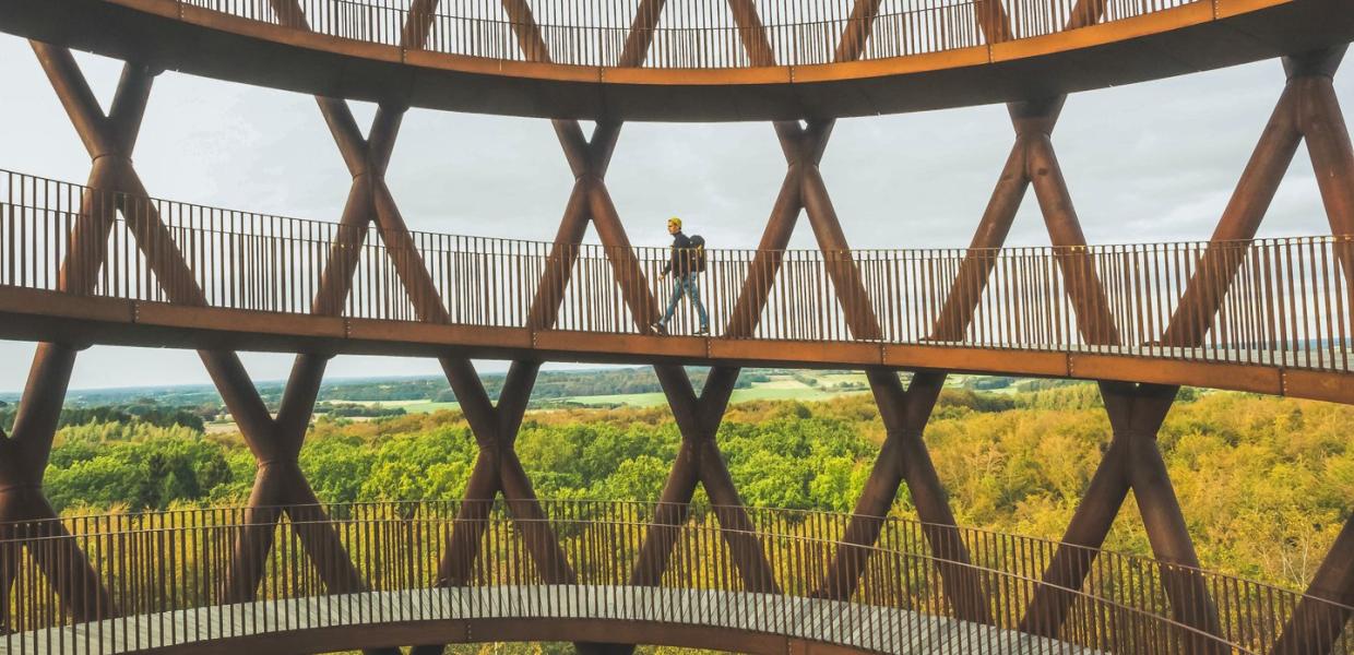 A man walks up Camp Adventure, a forest tower in Denmark.