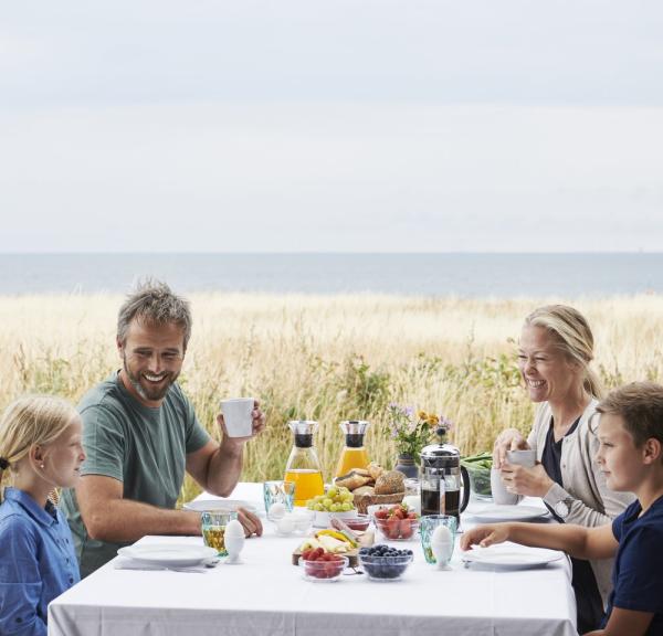Family having breakfast outside a holiday home in Nysted, Danmark