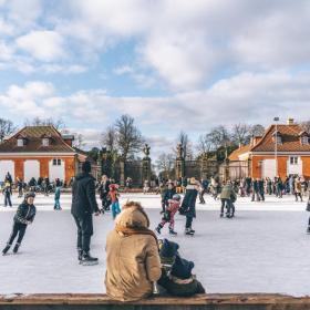 Barn og voksne står på skøyter utenfor Frederiksberg Have i København