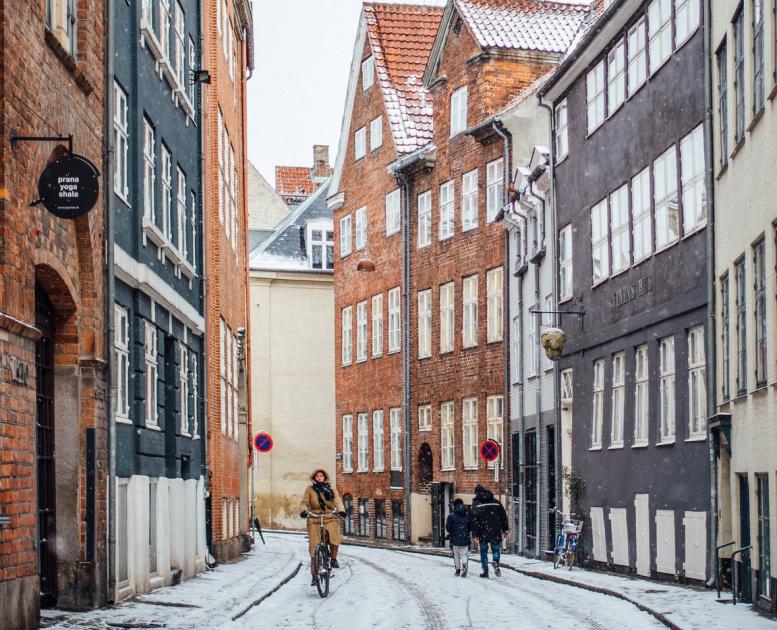A woman cycles down snowy Magstræde in Copenhagen, Denmark