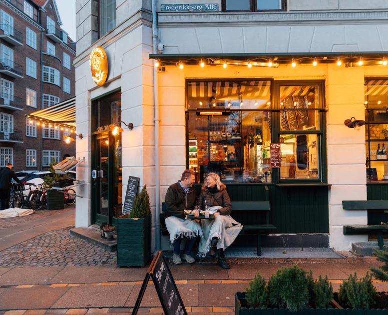 Et par sitter på en benk utenfor en kafe i København på vinteren